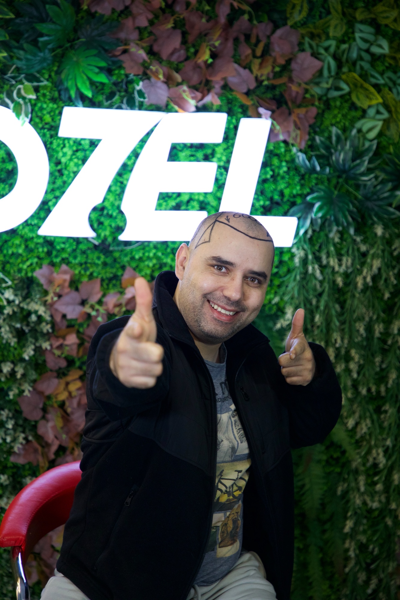 An OZEL client smiling and pointing at the camera with both hands