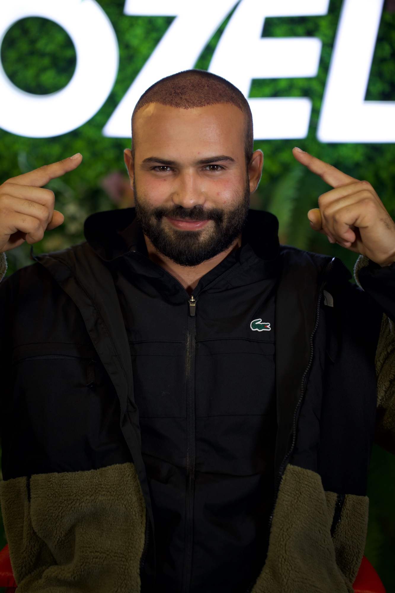 A smiling OZEL client pointing at his head